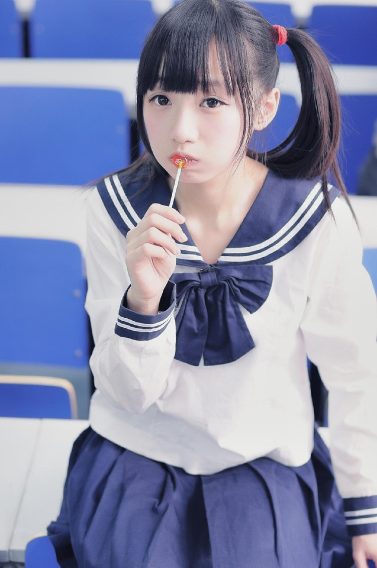 双马尾水手服少女吃棒棒糖时呆呆的神情