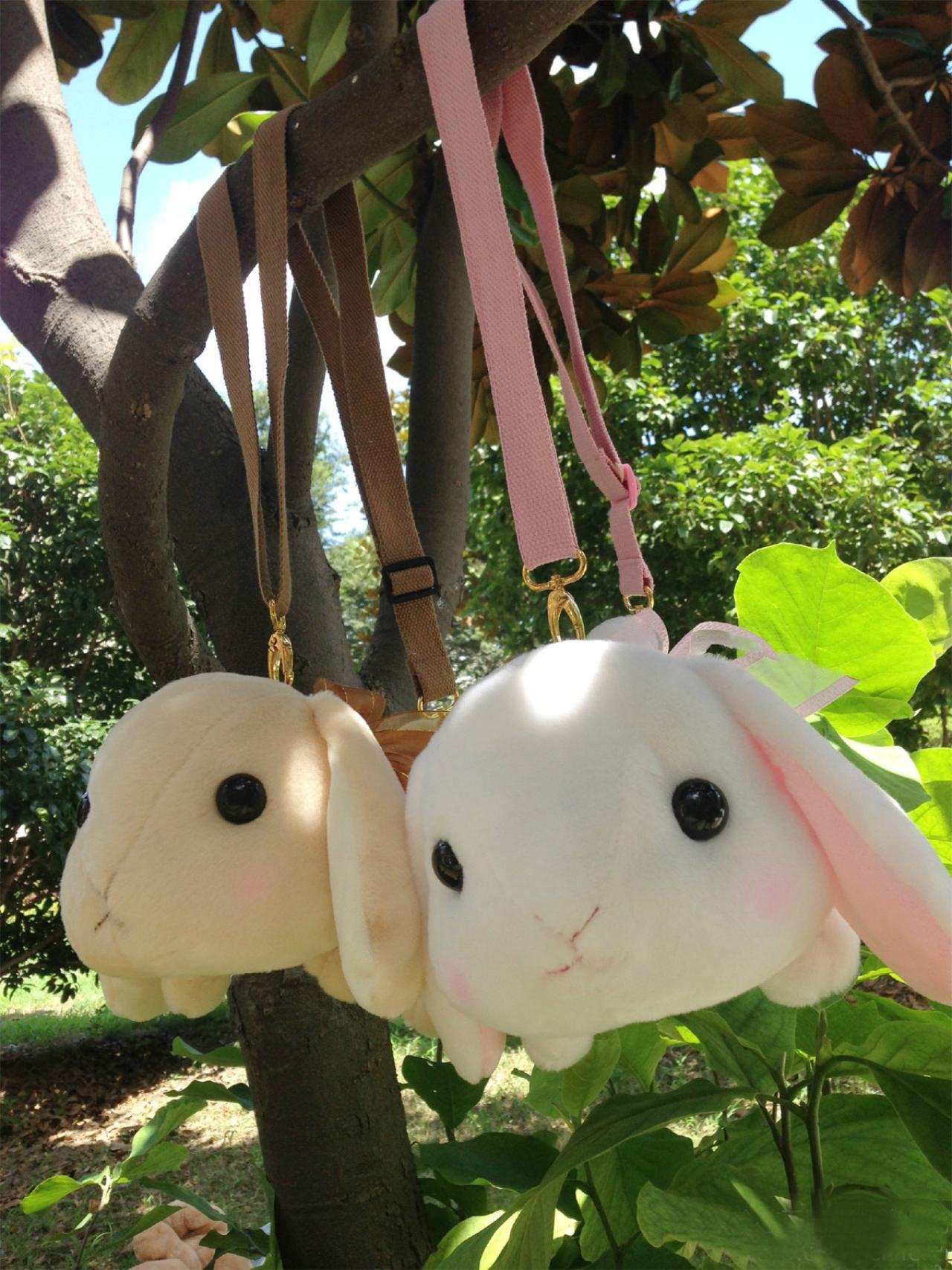 挂在树上的奶茶色和白色兔子背包