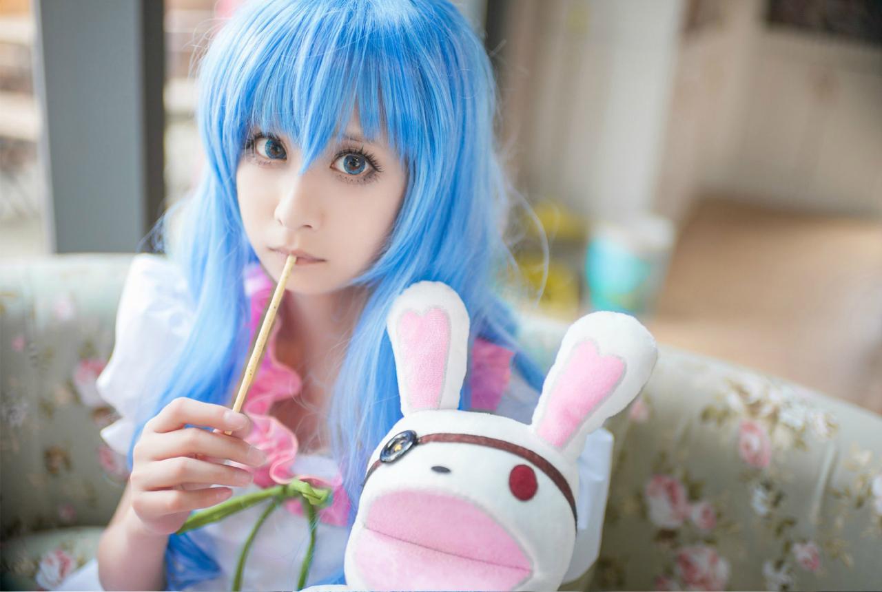 桃小陌扮演四糸乃拿着四糸奈兔子人偶坐在沙发上，嘴里抿着一长条饼干。