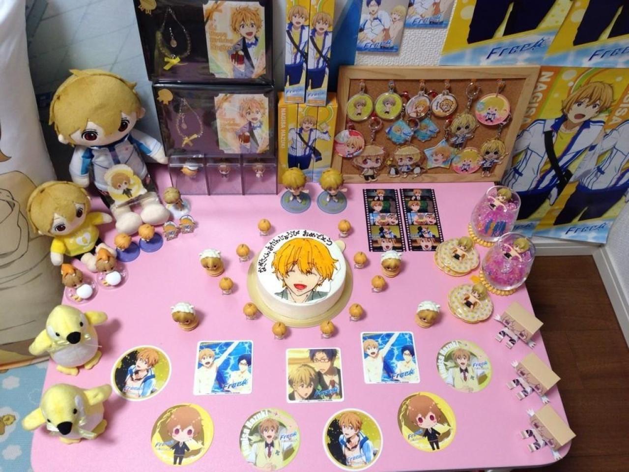 粉红的桌面上摆满了叶月渚蛋糕，贴纸，纸膜，粘土手办和玩偶