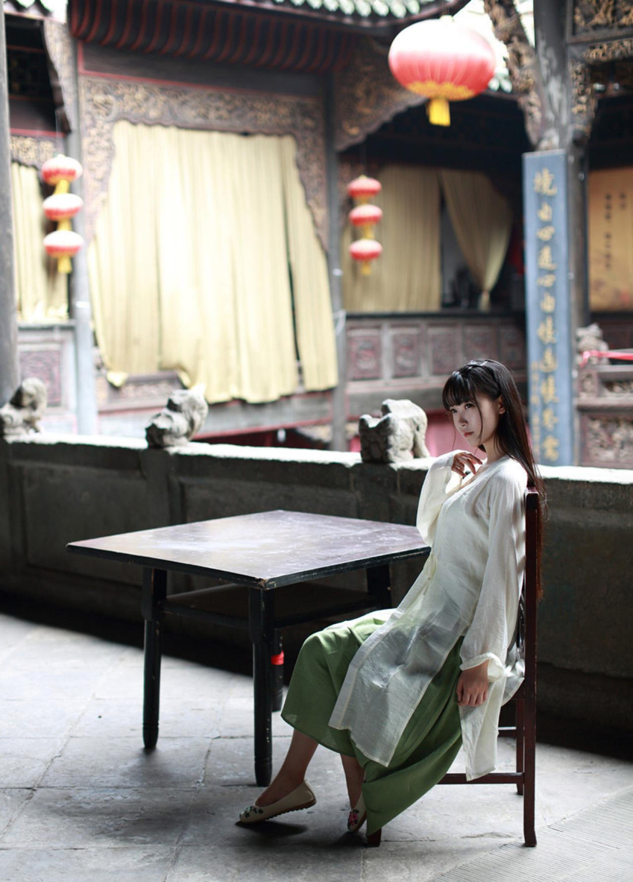 半藏森林穿着白色对襟褙子长款上衣斜靠在方桌旁的木椅上