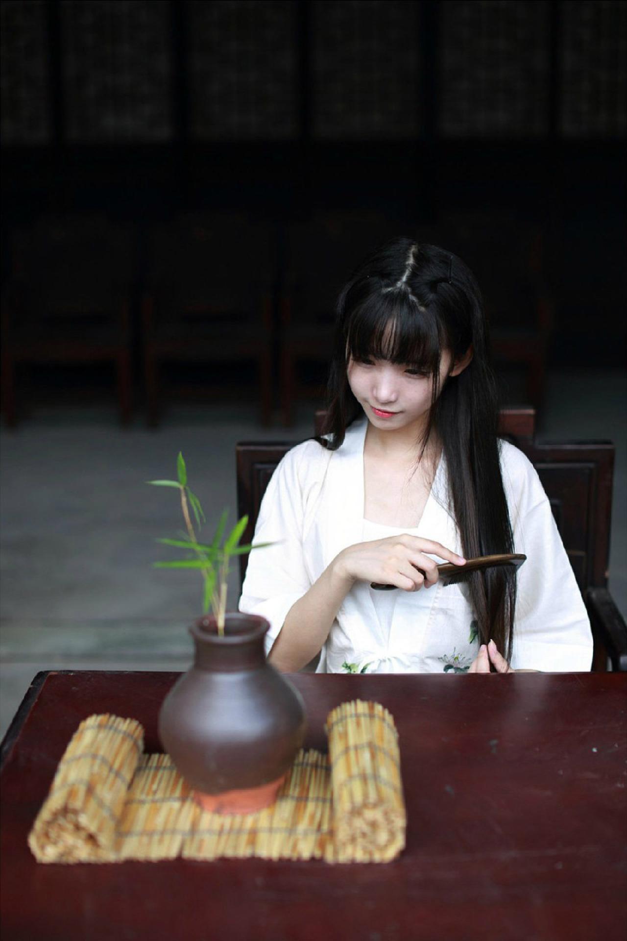 半藏森林穿着白色对襟褙子长款上衣靠在木椅上用木梳梳理长发