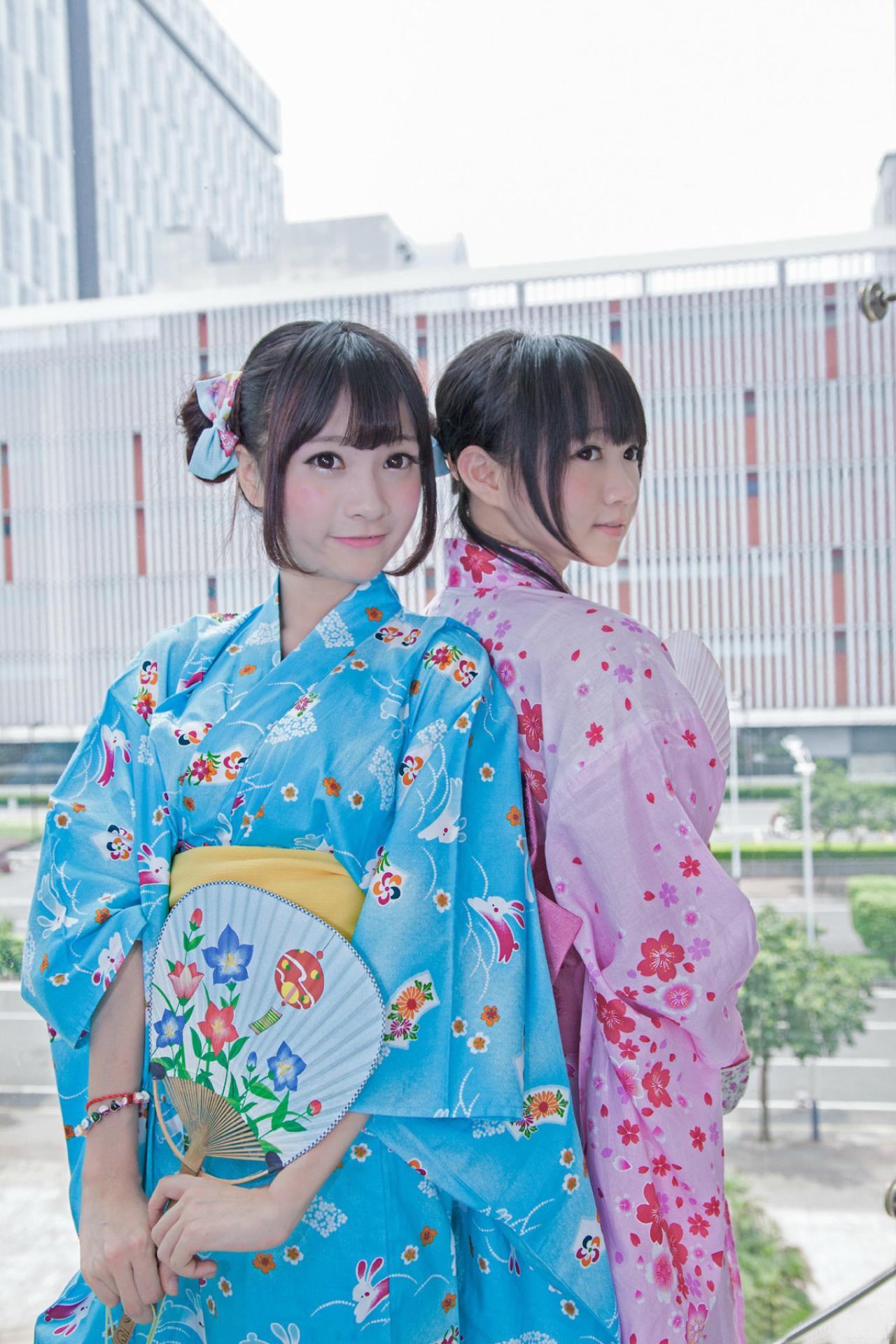 橘子酱和小龟在靠窗的展位，背靠背各自拿着一面扇子的姿势 路过摄影