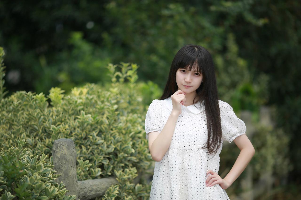 苏里柟穿着白色波点罩衫略微倾斜身子叉腰站立