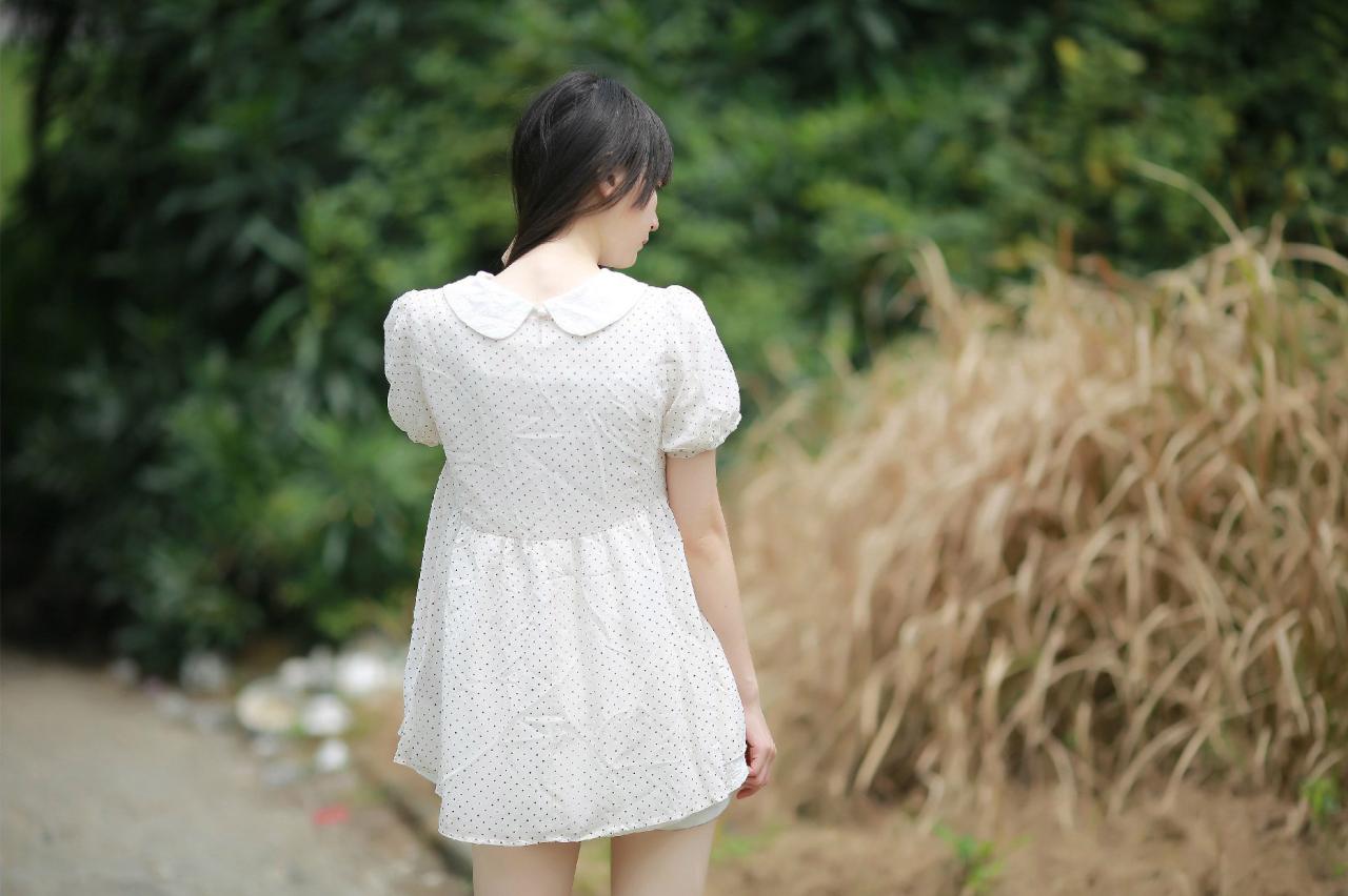苏里柟穿着白色波点罩衫将长头发抓起，露出脖颈的背面