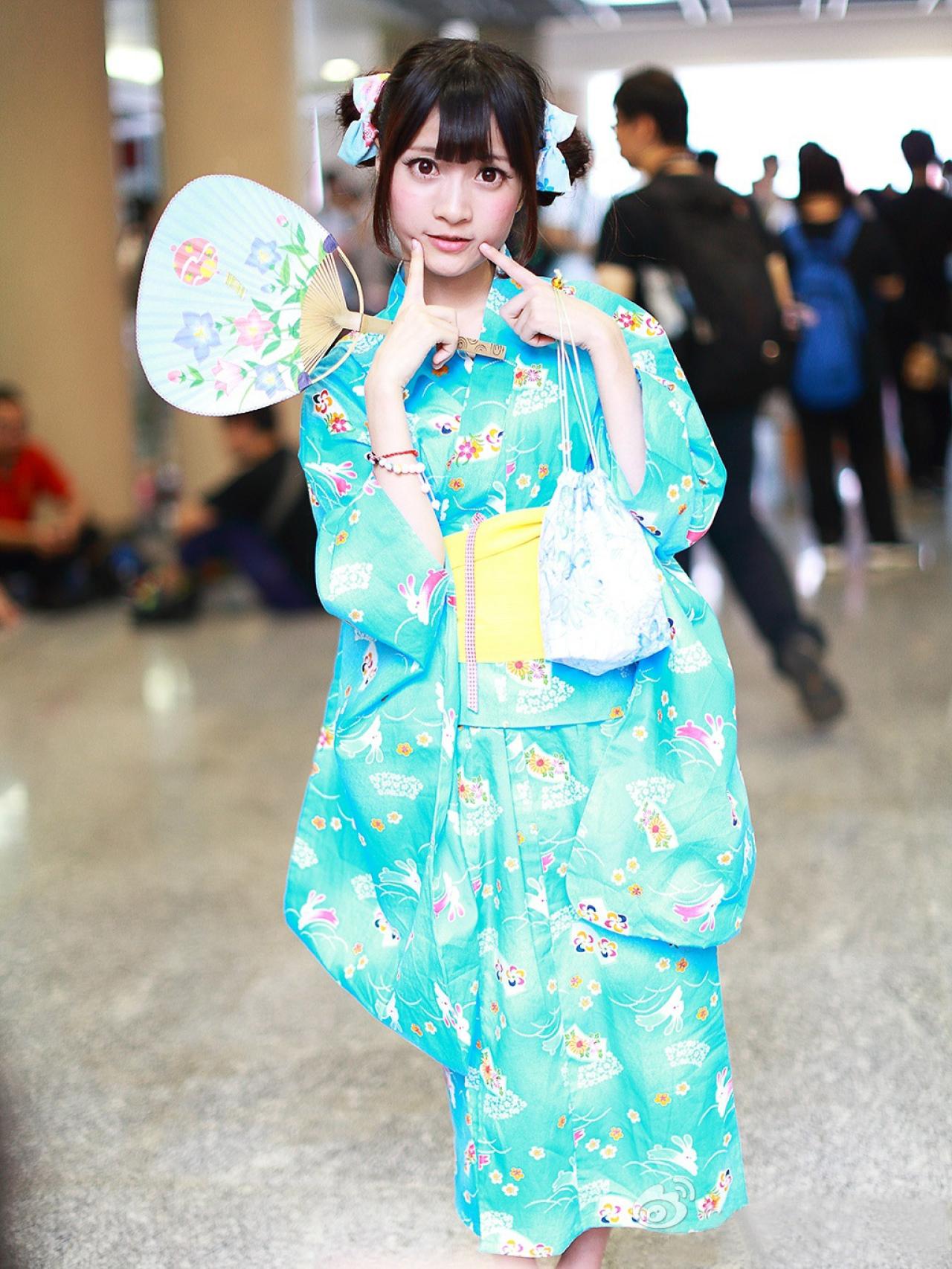 橘子酱右手持扇，双手手指按着两侧脸颊卖萌 孤岛桑-MccVision拍摄