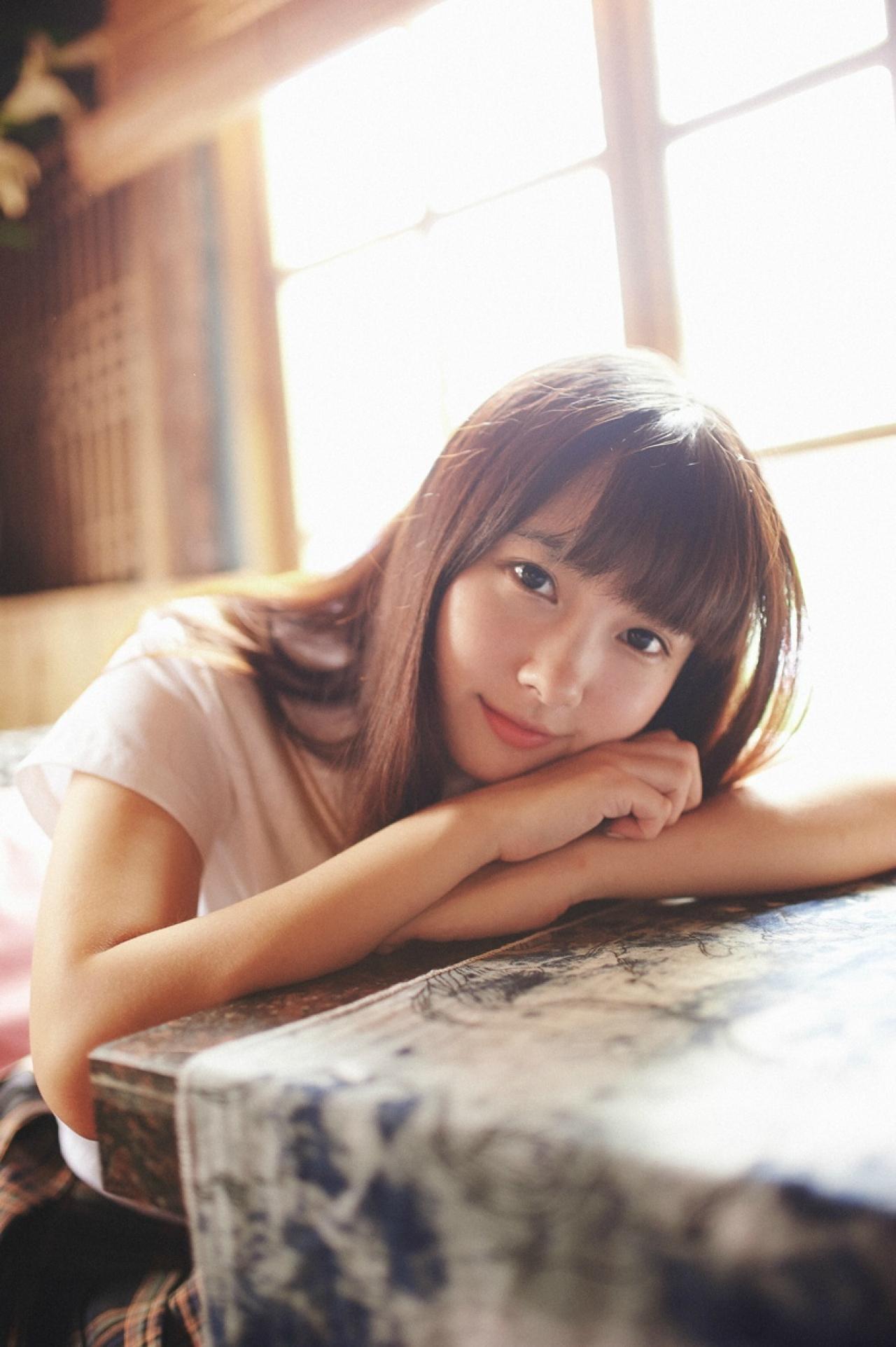 山田実瑠扒在桌子上，对着镜头微笑