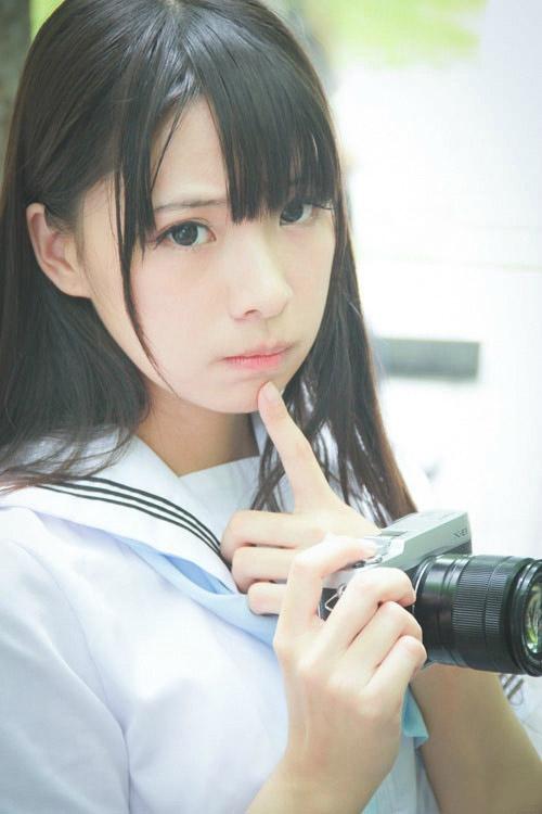 贤儿sherry穿着水手服右手拿着相机，左手用手指抵着下巴，嘟嘴卖萌的姿势