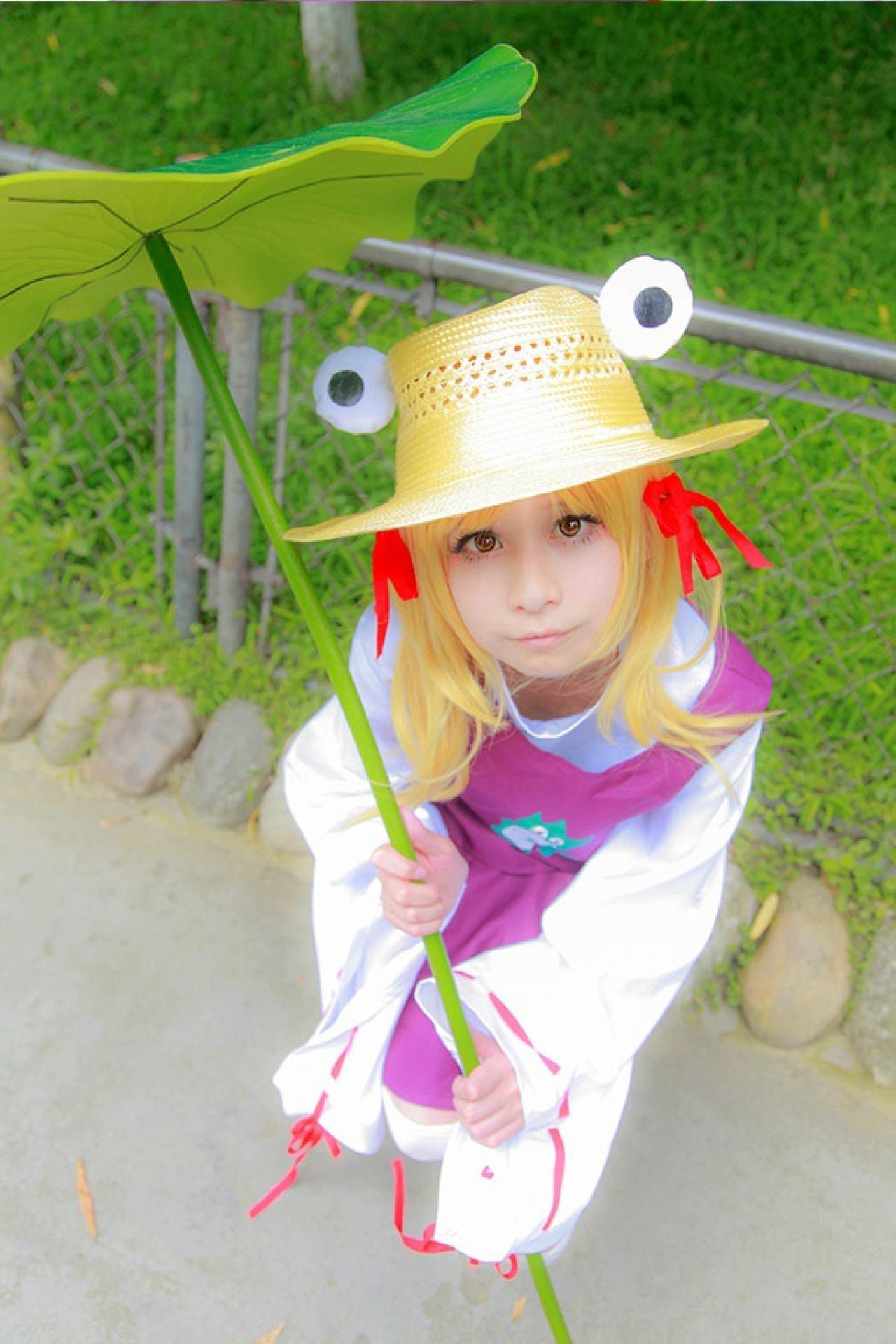 桃小陌扮演泄矢诹访子拿着荷叶茎秆坐在路旁的石头上