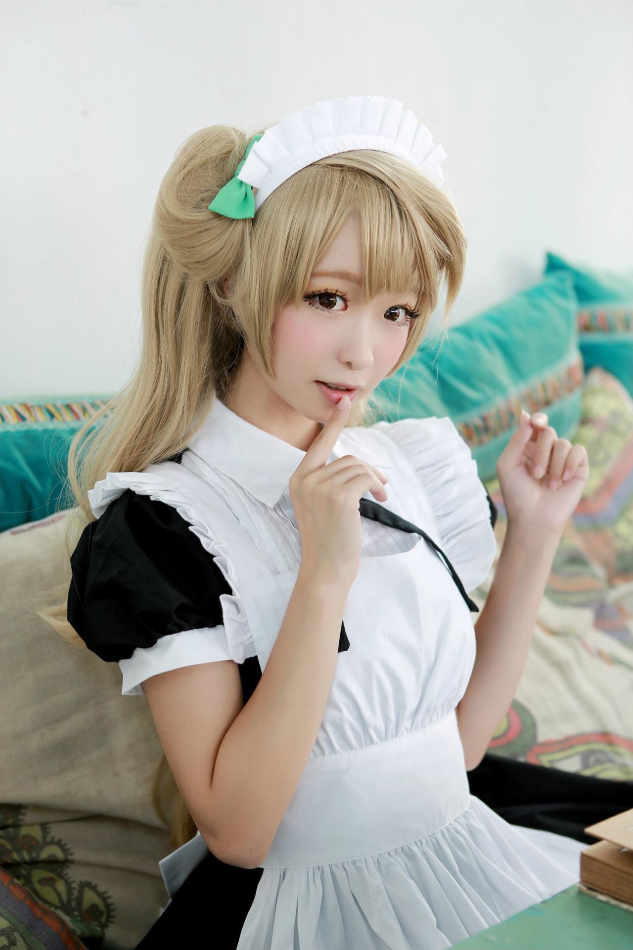 鳄鱼同学扮演南小鸟坐在沙发上弯曲双臂，右手食指抵着下嘴唇的姿势