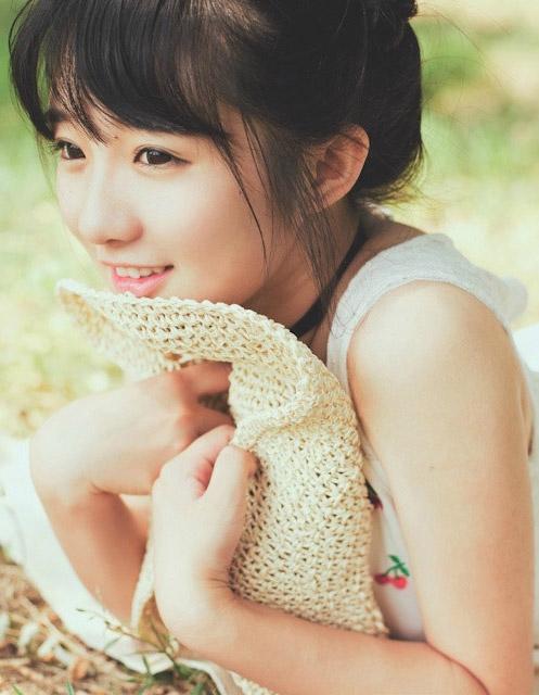 小陆离将草帽抱紧在胸前，微笑的神情 脸部特写