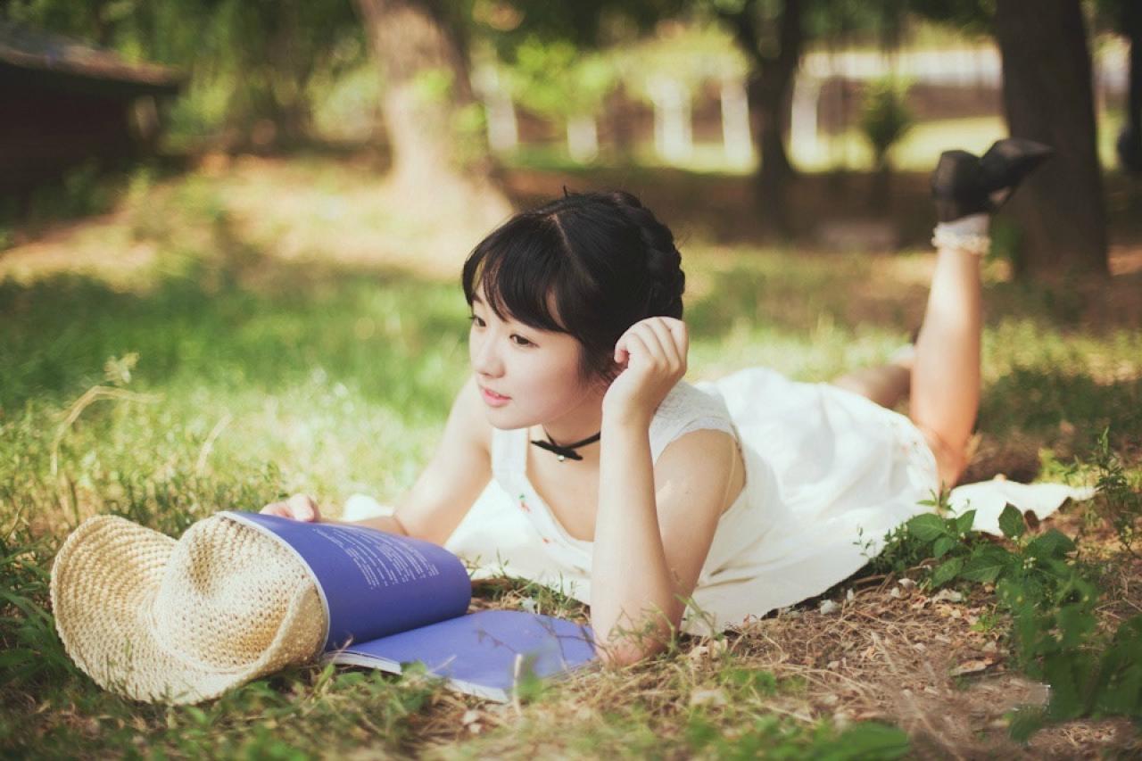 小陆离扒在草地上，翘着腿，翻阅着一本紫色的书