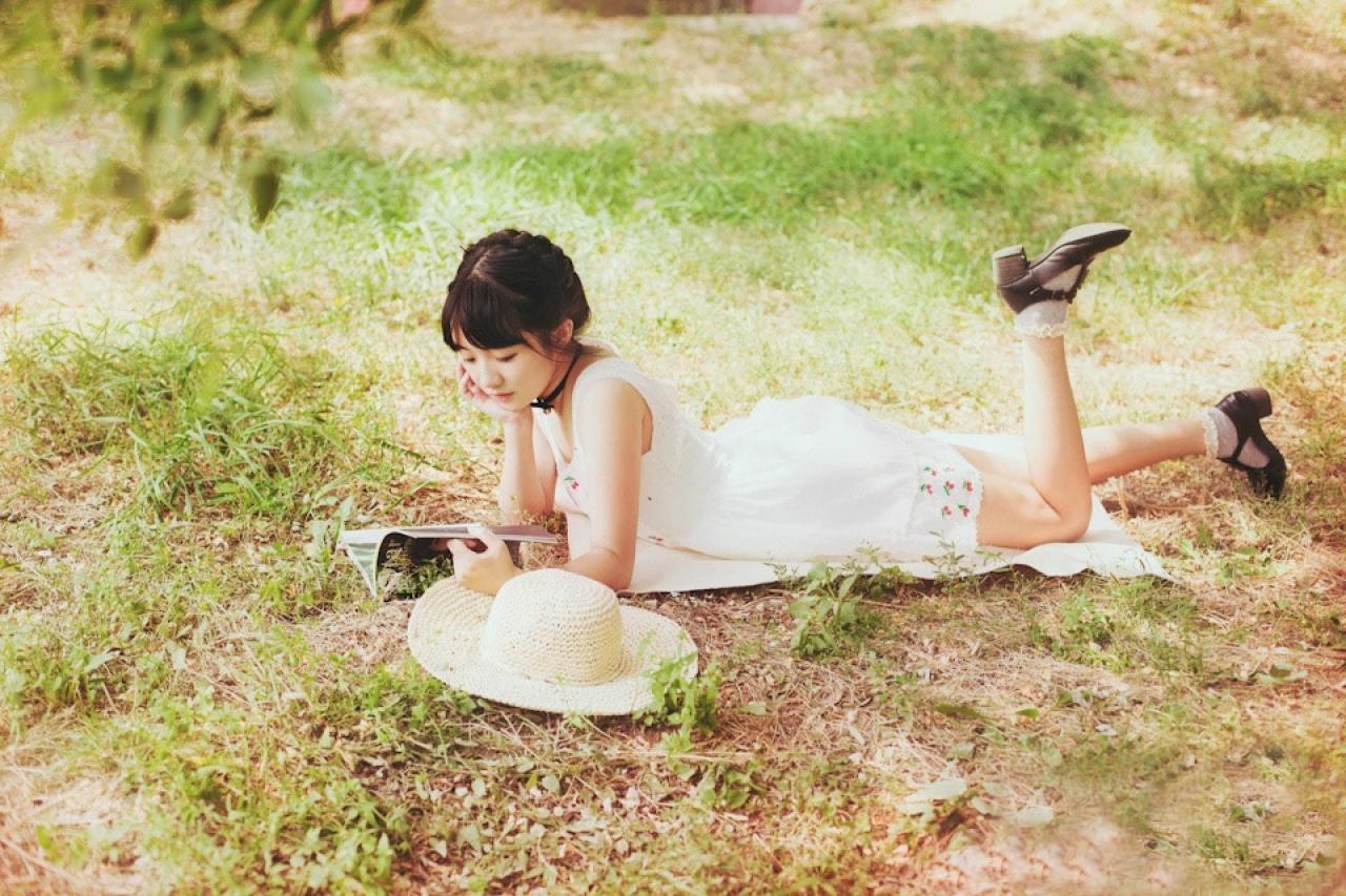 小陆离扒在草地上看书的全身照