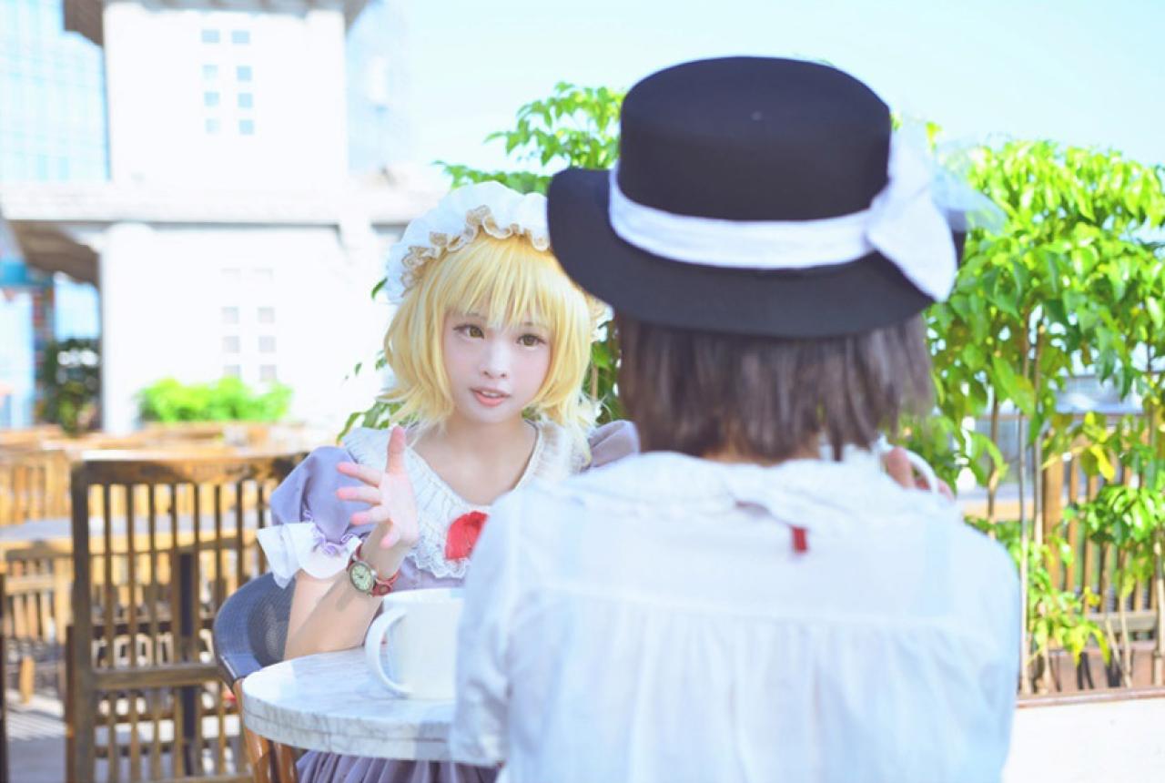 森森咒仙扮演魔术师梅莉和胡桃扮演的宇佐见·莲子面对面，梅莉用手比划着和莲子交谈