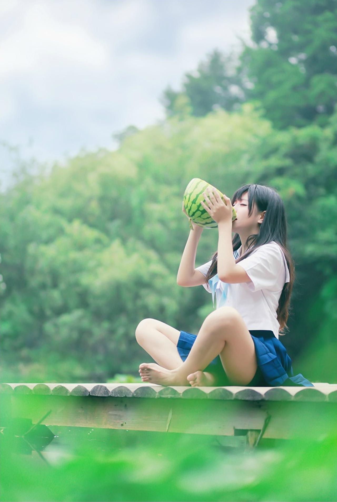 流一坐在墙上，抱着一半西瓜，长大嘴巴喝西瓜汁的样子