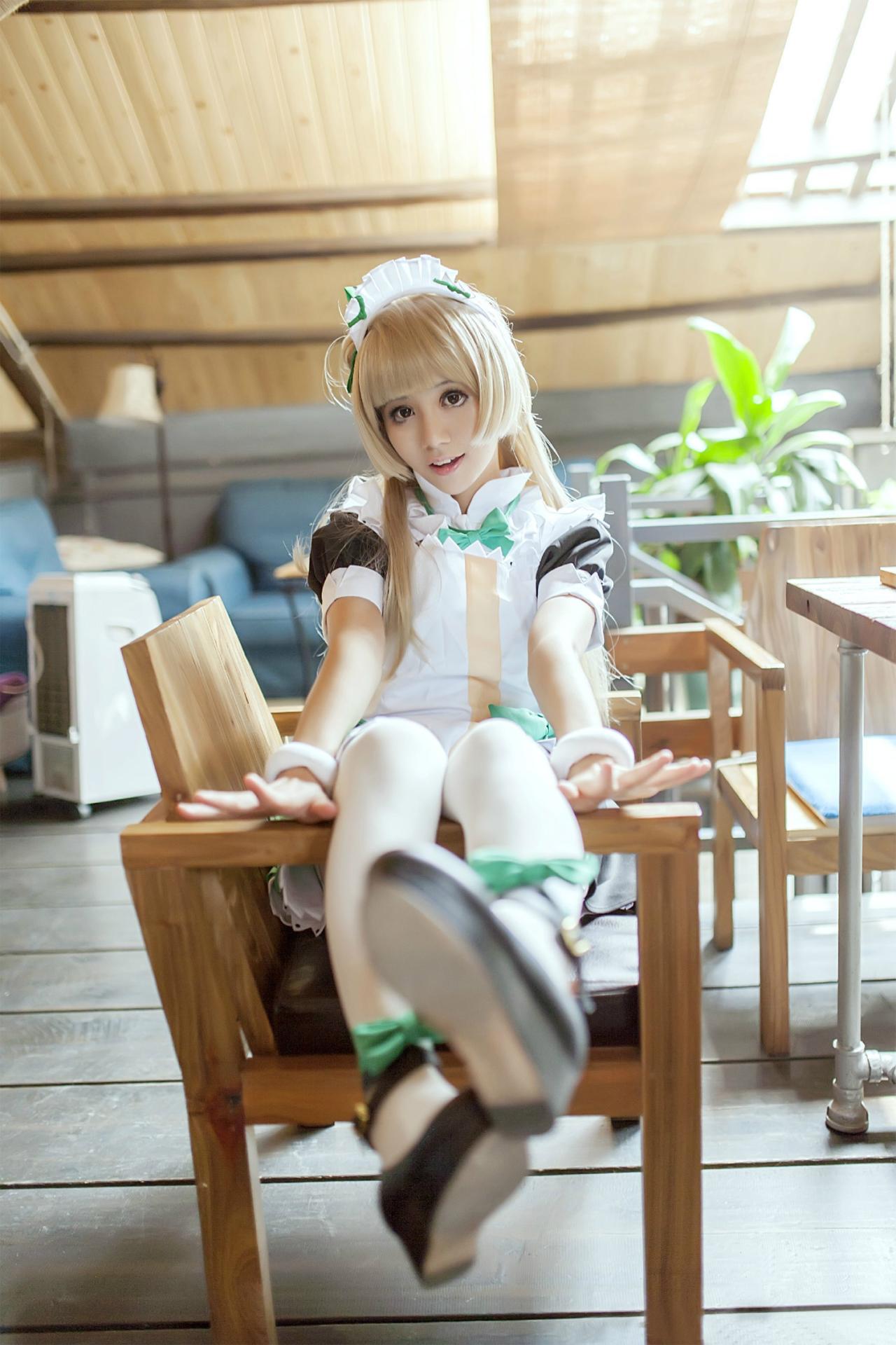 冰夜酱扮演南小鸟侧坐在木椅上，双腿搭在椅子扶手，歪着头笑着