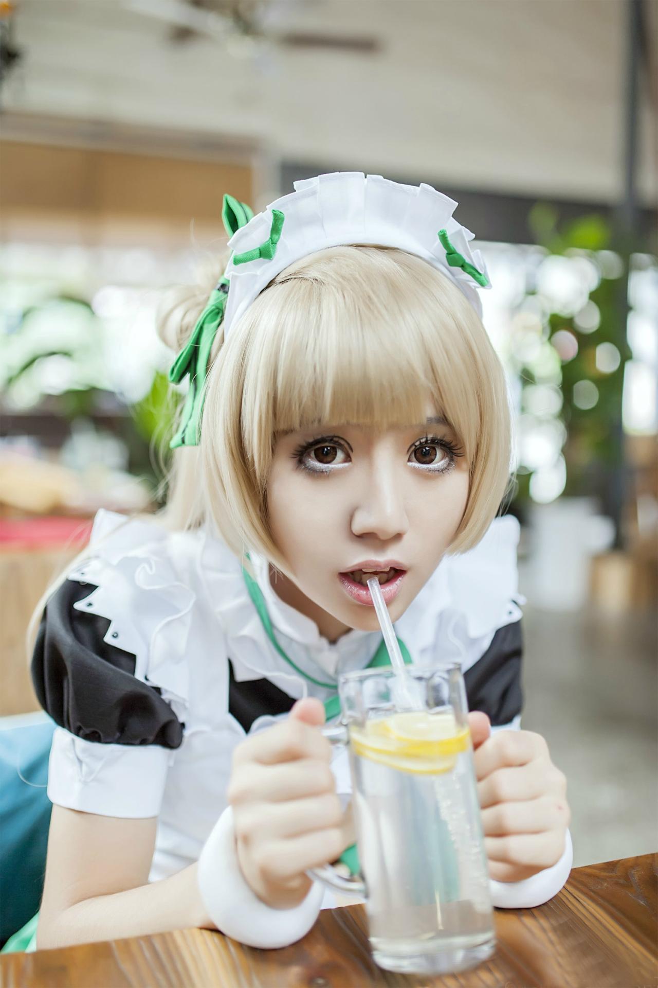 冰夜酱扮演南小鸟双手捧着杯子，扒在桌子上，张大嘴巴，准备吸柠檬汁