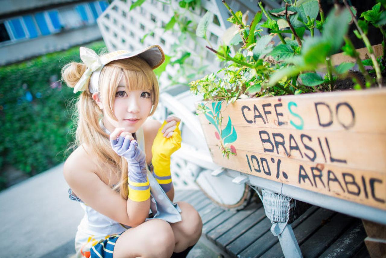 黑川扮演南小鸟蹲在印有CAFES DO BRASIL 100% ARABIC字样的牌子前