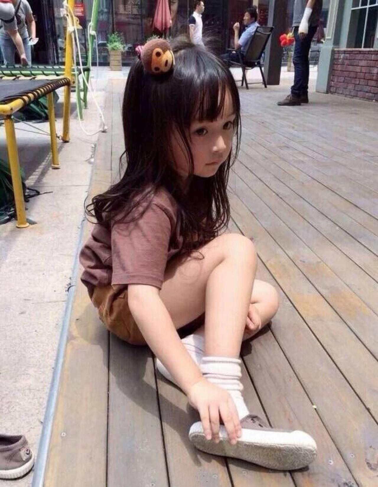 坐在地板上，正在脱右脚鞋子的小萝莉