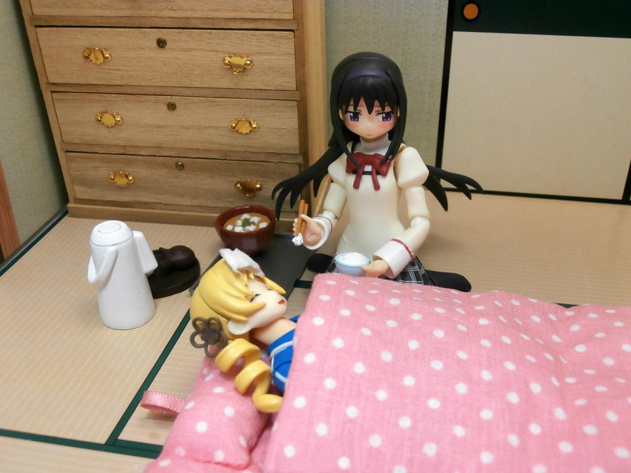 巴麻美的手办躺在被窝里发烧了，晓美焰的手办不好意思地给巴麻美夹饭喂她吃