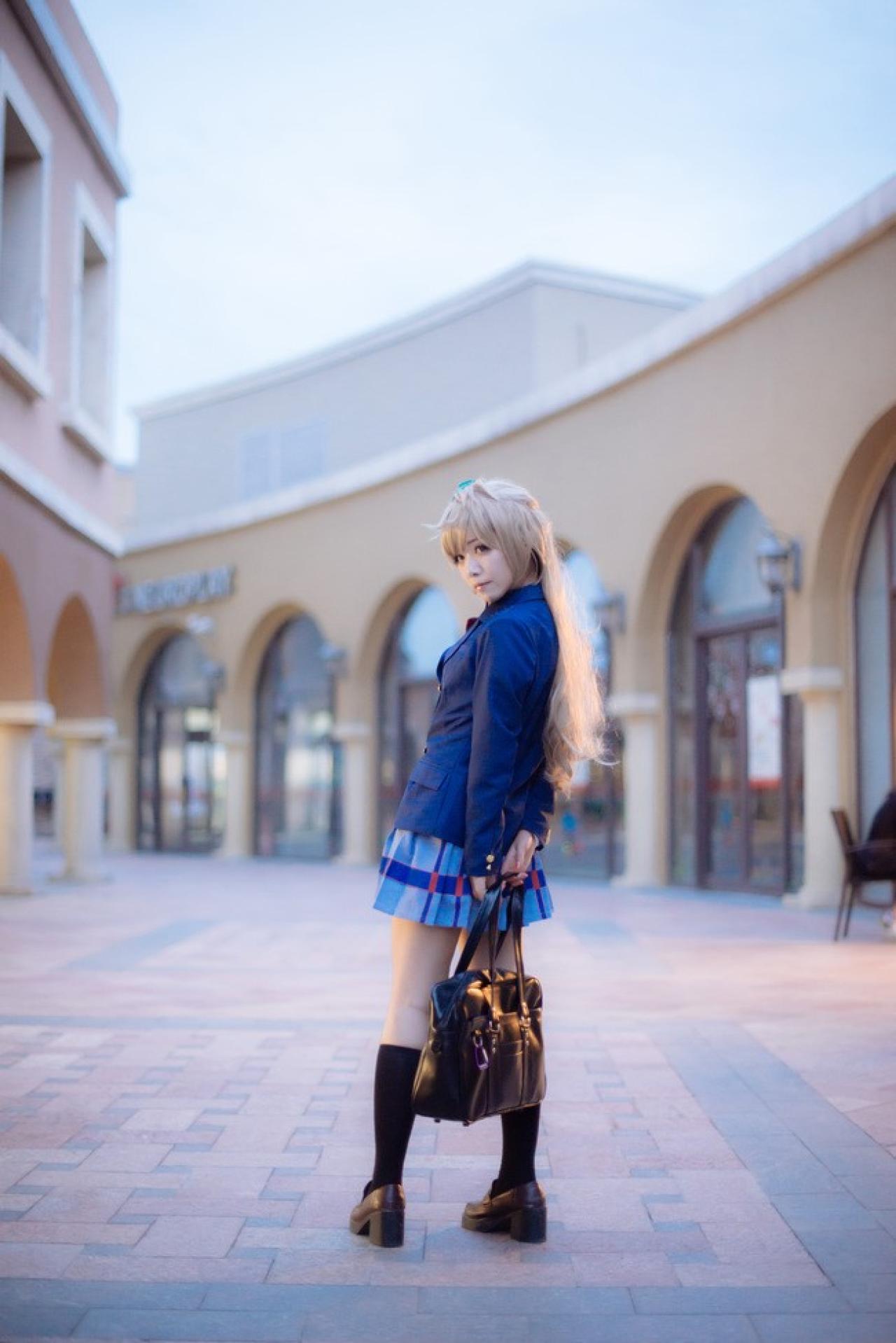 四月www扮演南小鸟双手放在背后，提着背包，扭身看镜头