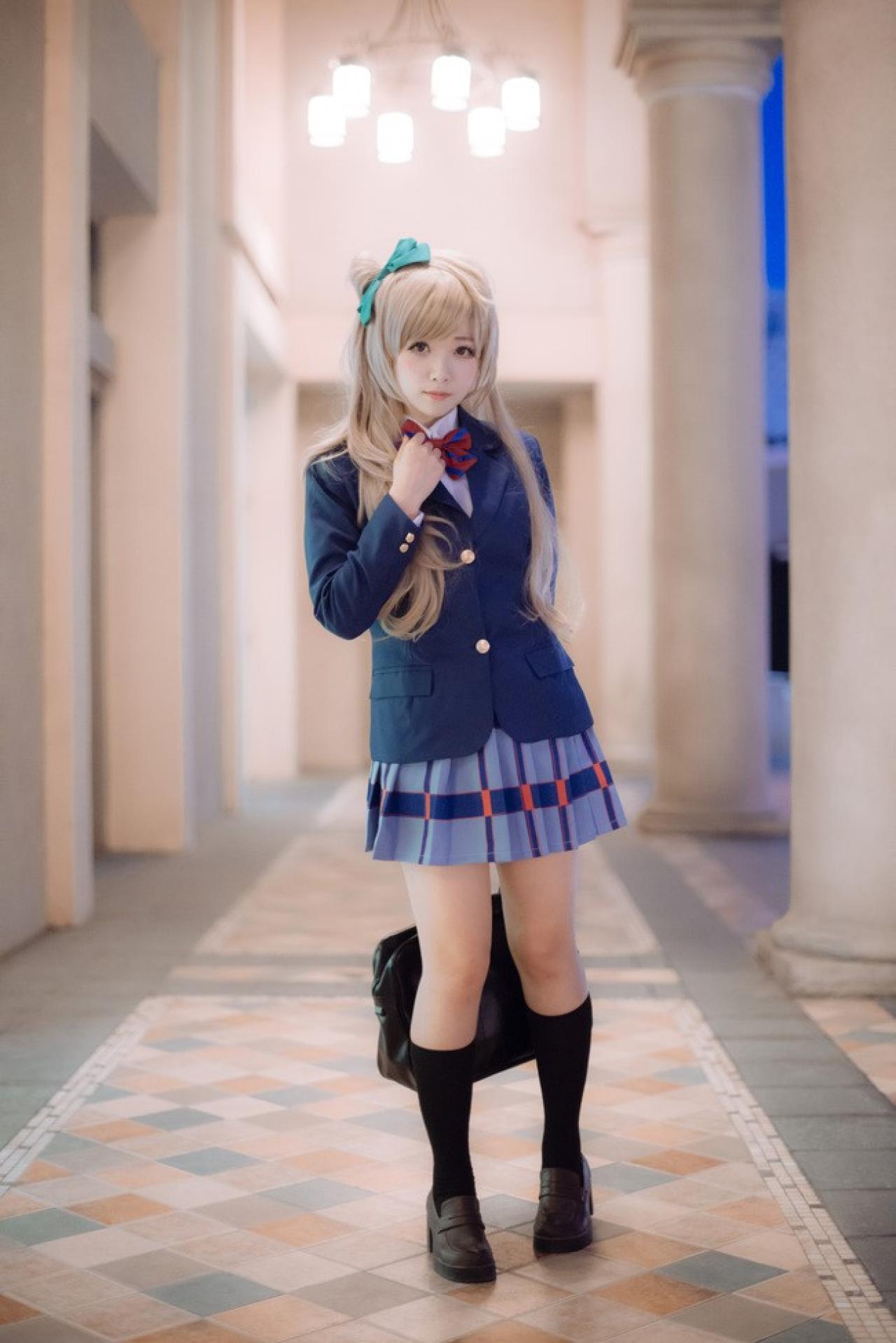 四月www扮演南小鸟左手放在背后提着包，右手按着蝴蝶结的姿势