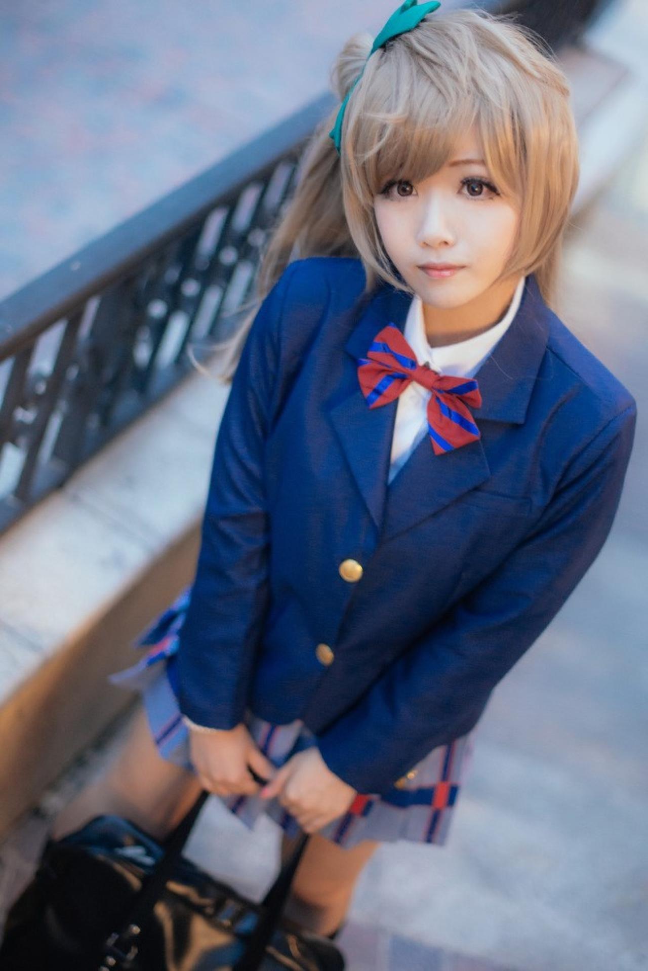 四月www扮演南小鸟双手叠放在眼前，提着包。