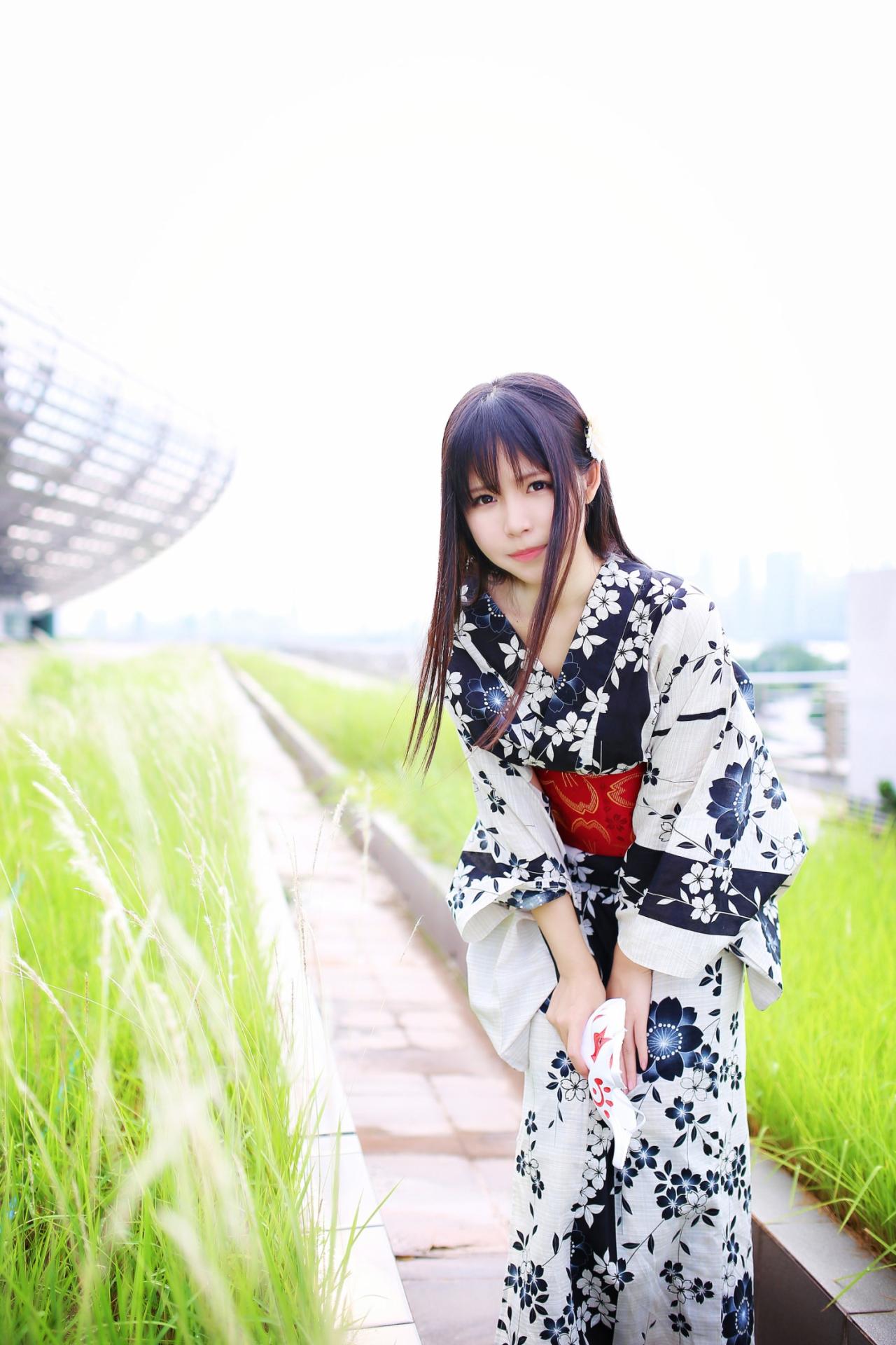 安姐姐站在草池中间，弯着腰俯身的姿势，微侧面