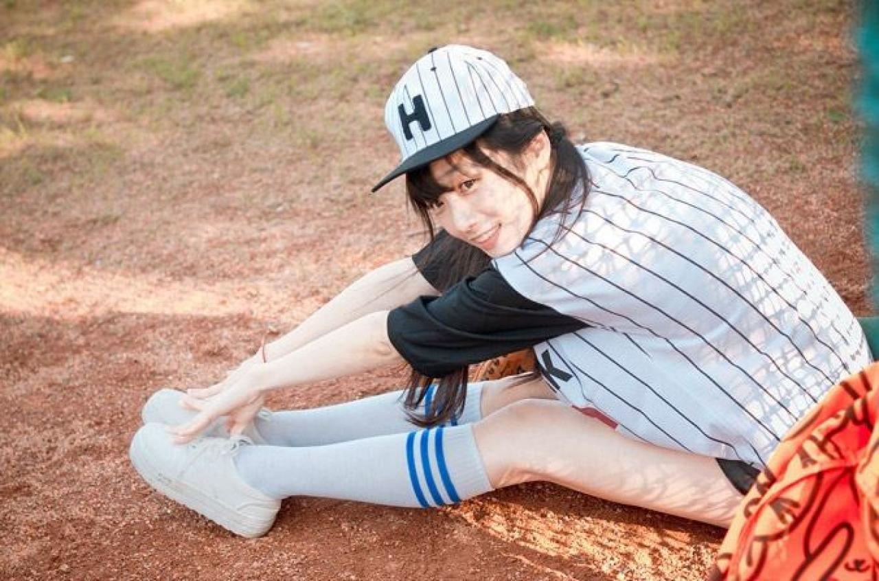 馋宝宝靠在棒球网上，作坐位体前屈姿势