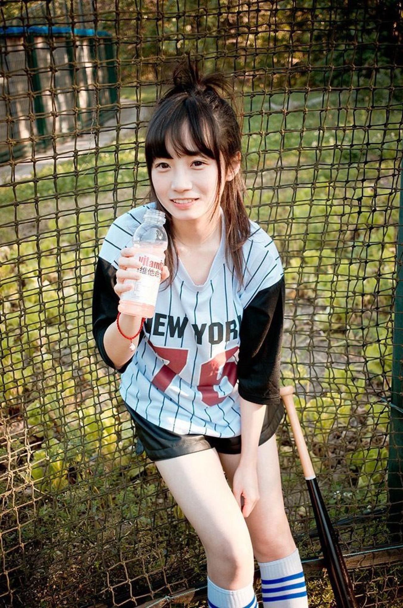 馋宝宝靠在棒球网上，略微躬着身子，右手拿着维他命水的姿势