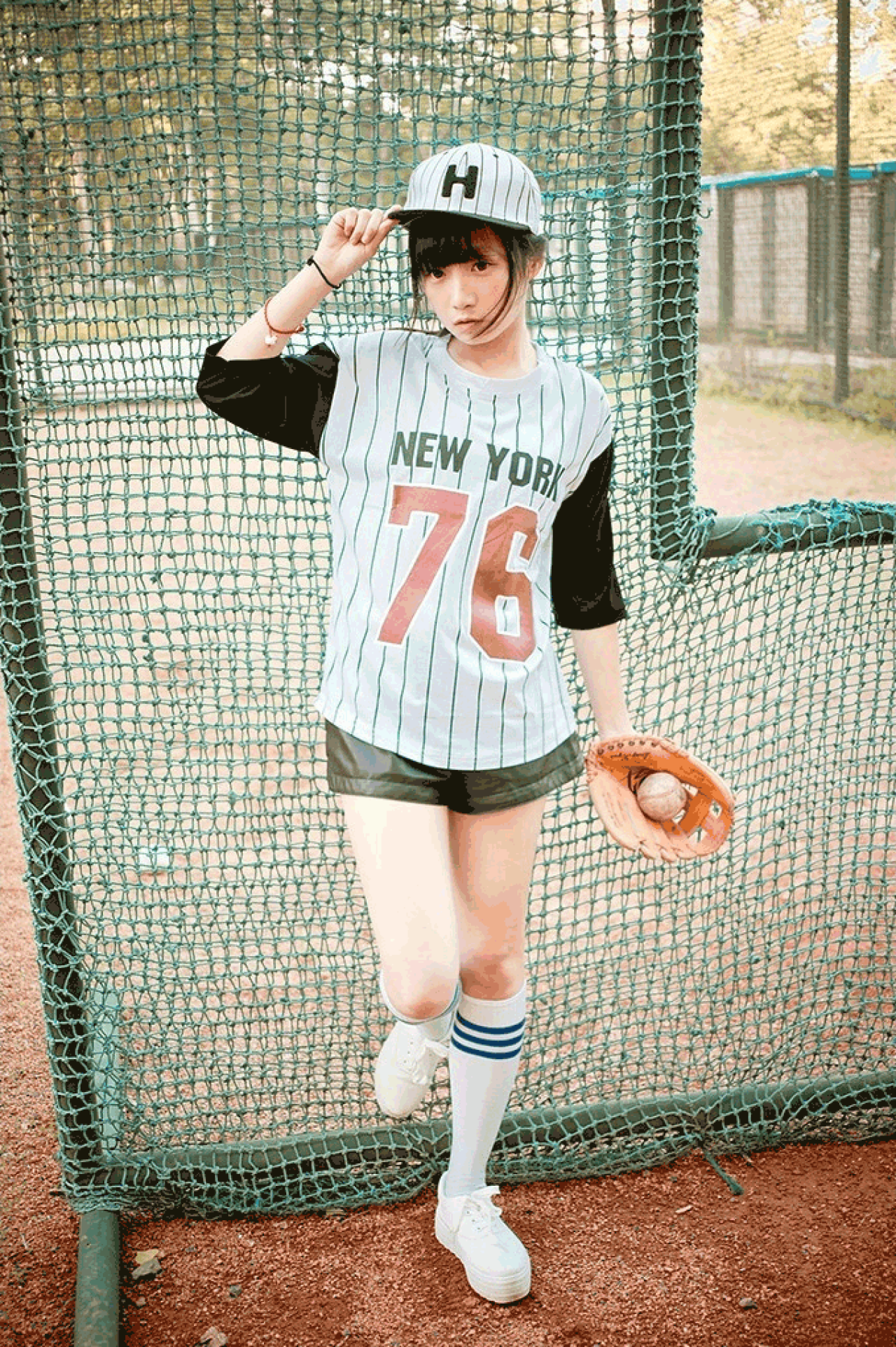 馋宝宝左手握着棒球，右手扶正棒球帽的全身照