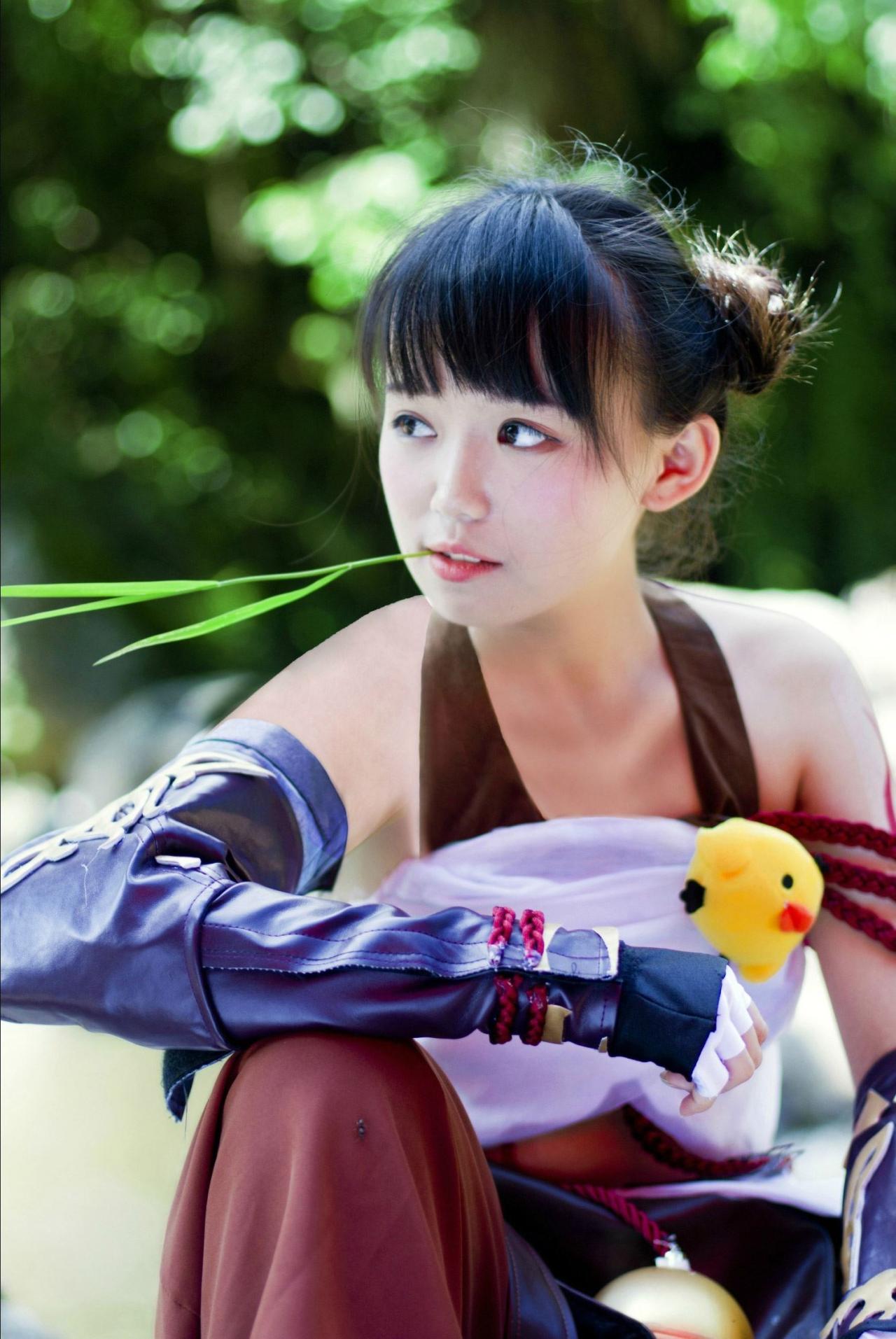 修老虎扮演丐帮萝莉将草叶叼在嘴里，坐在石头上，右手弯曲枕在膝盖上，目光轻蔑，有点女汉子或女侠的气质形象