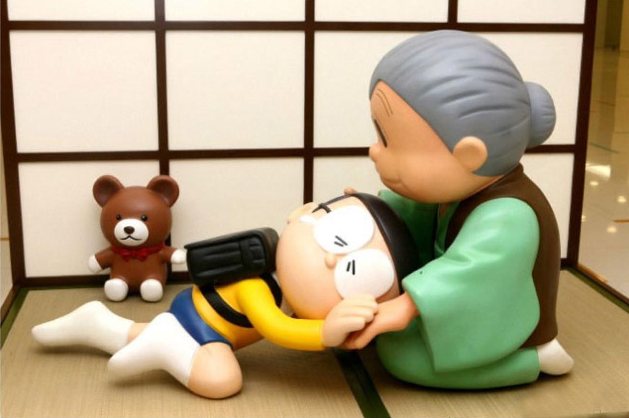 哆啦A梦展览中，野比大熊将头靠进奶奶怀里，奶奶用手摸着野比大雄头的手办照片