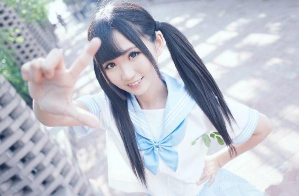 姗酱左手叉腰按着一柳绿叶，右手朝镜头作八字手势的上半身照