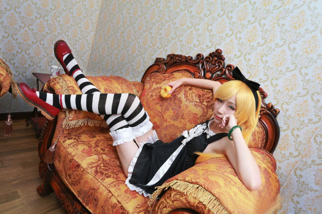 下北原喵扮演忍野忍躺在沙发里，右手拿着甜甜圈