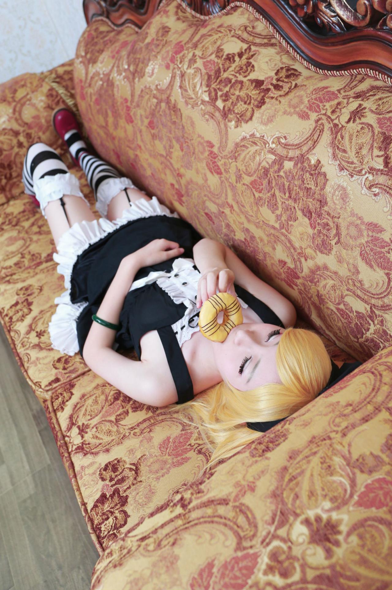 下北原喵扮演忍野忍躺在沙发上，吃甜甜圈