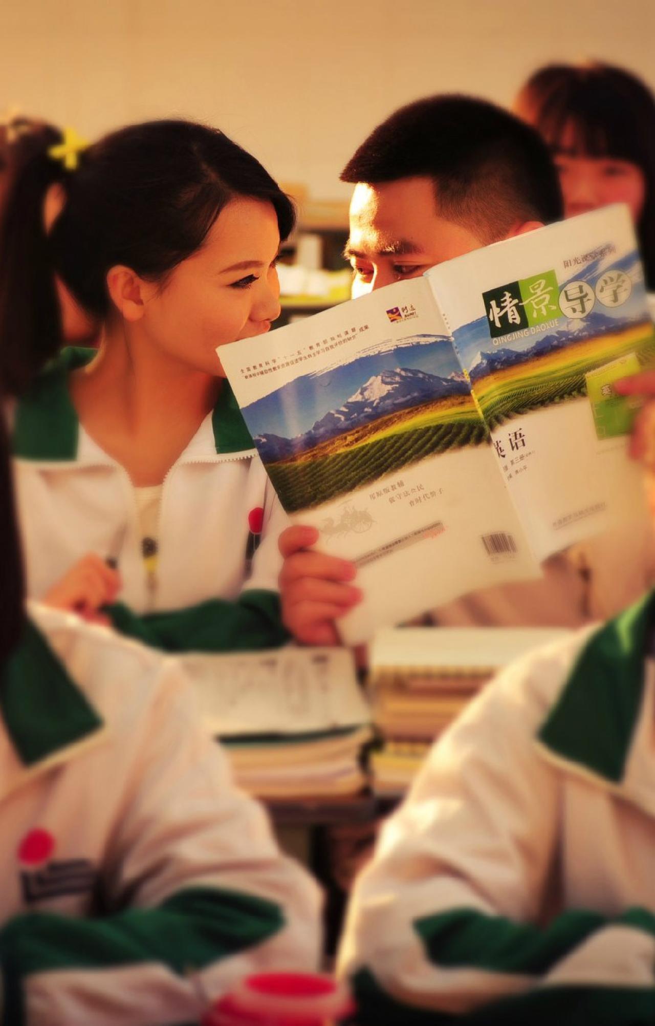 正在说悄悄话的同桌，男孩用课本遮挡脸部 温江Vv视觉拍摄