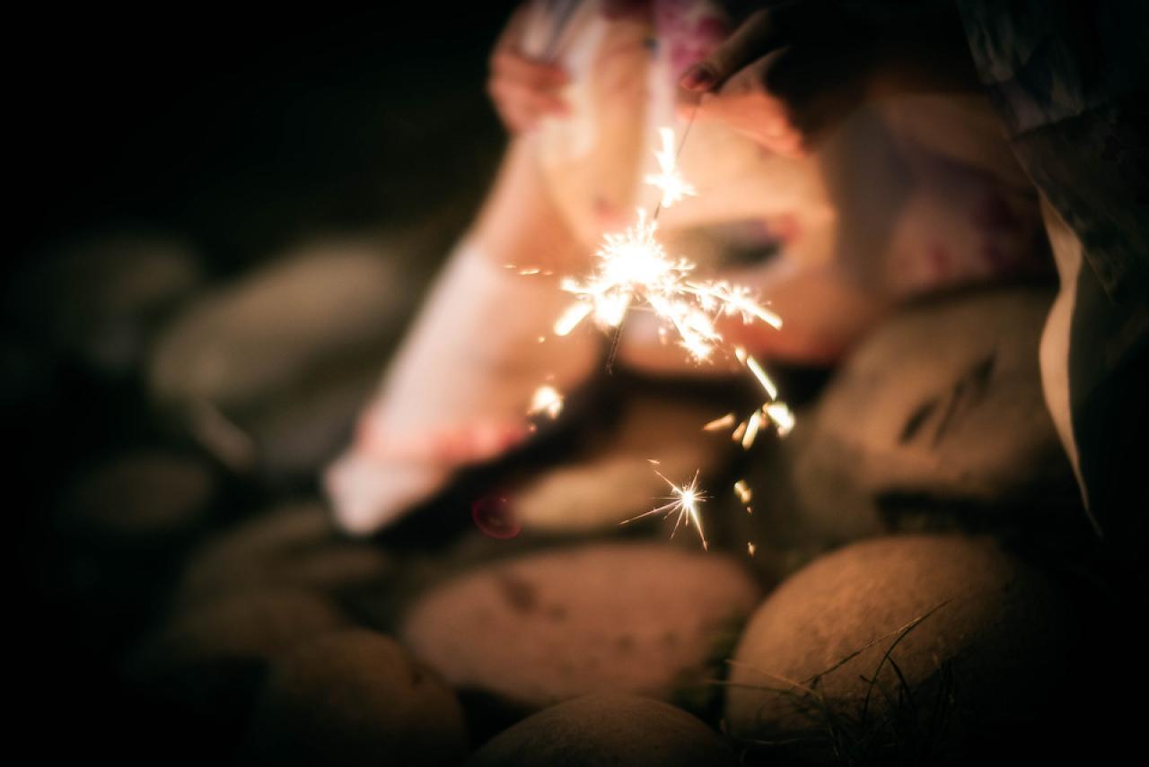 雪雪右手抱着膝盖，左手手中仙女棒的花火特写