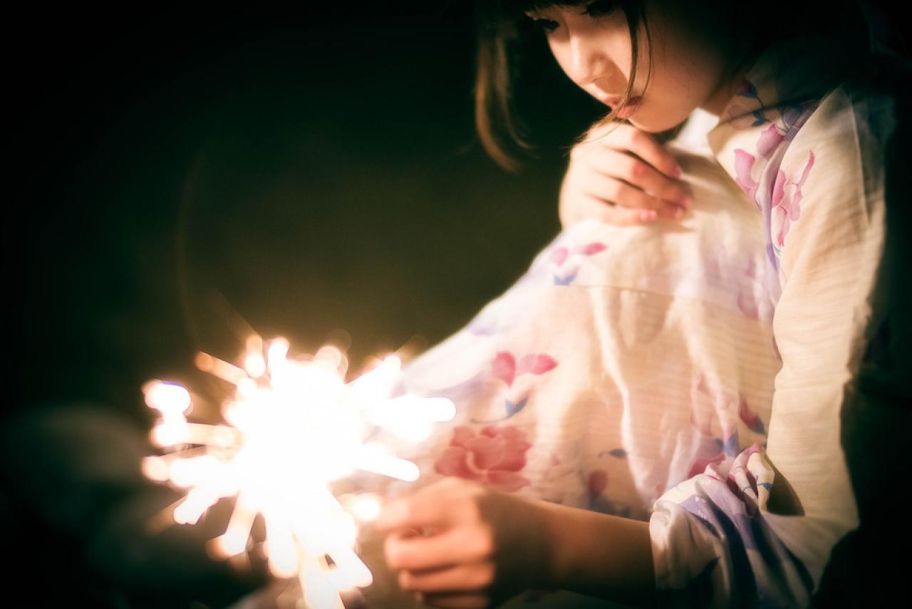 雪雪抱着膝盖坐着，点燃仙女棒的侧面照