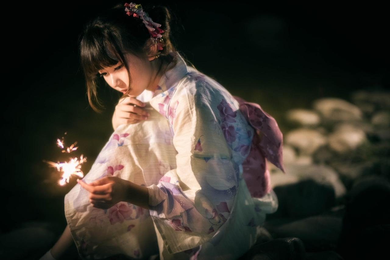 雪雪抱着膝盖，弓着腰，低着脑袋看着右手手中燃烧的仙女棒