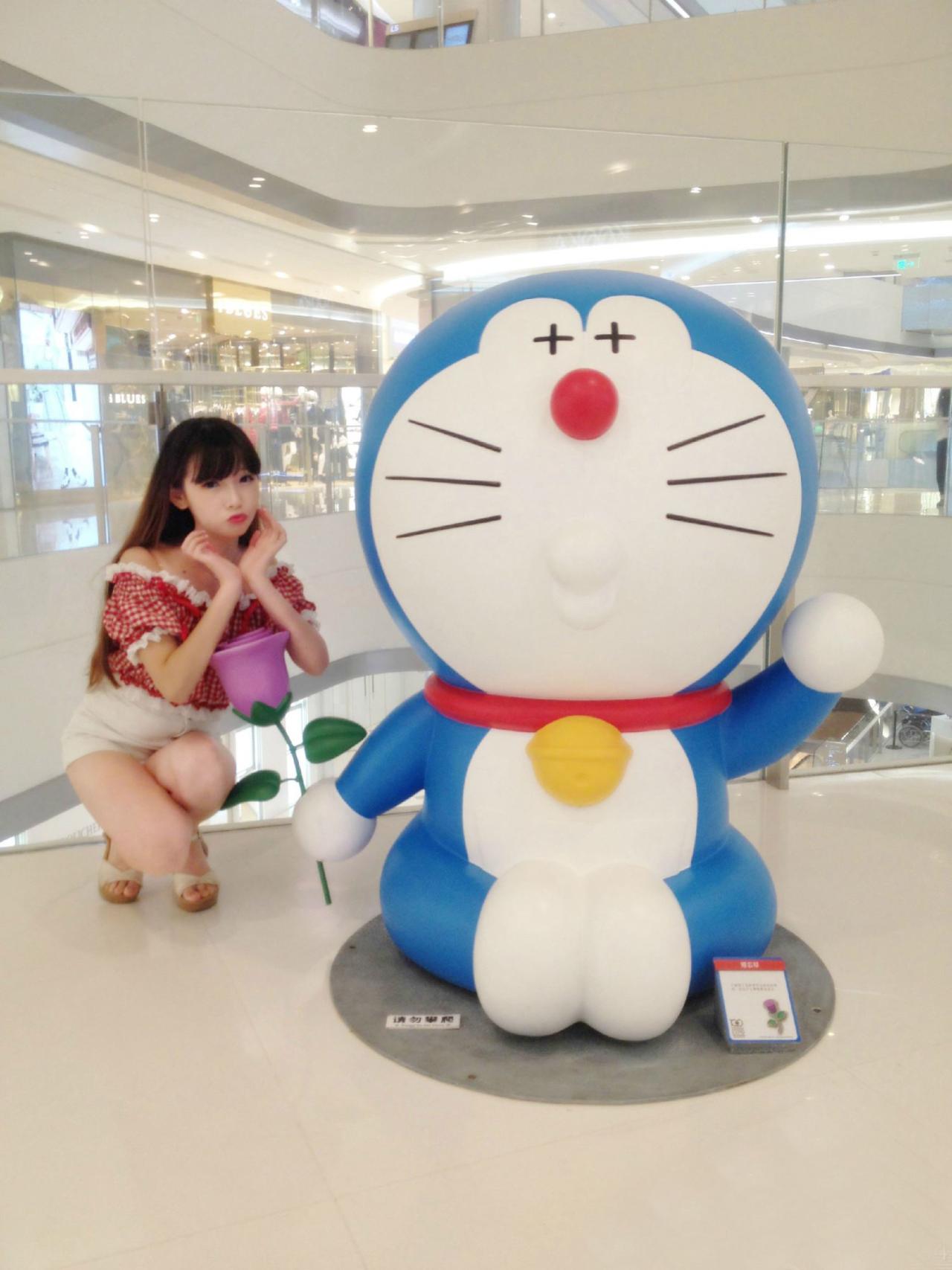 雪雪嘟嘴卖萌和拿着紫色花朵的哆啦A梦合影