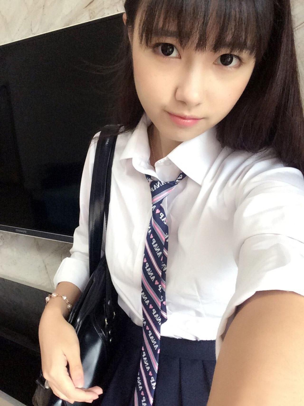 MILU挎着黑色皮包，身后墙上挂着电视