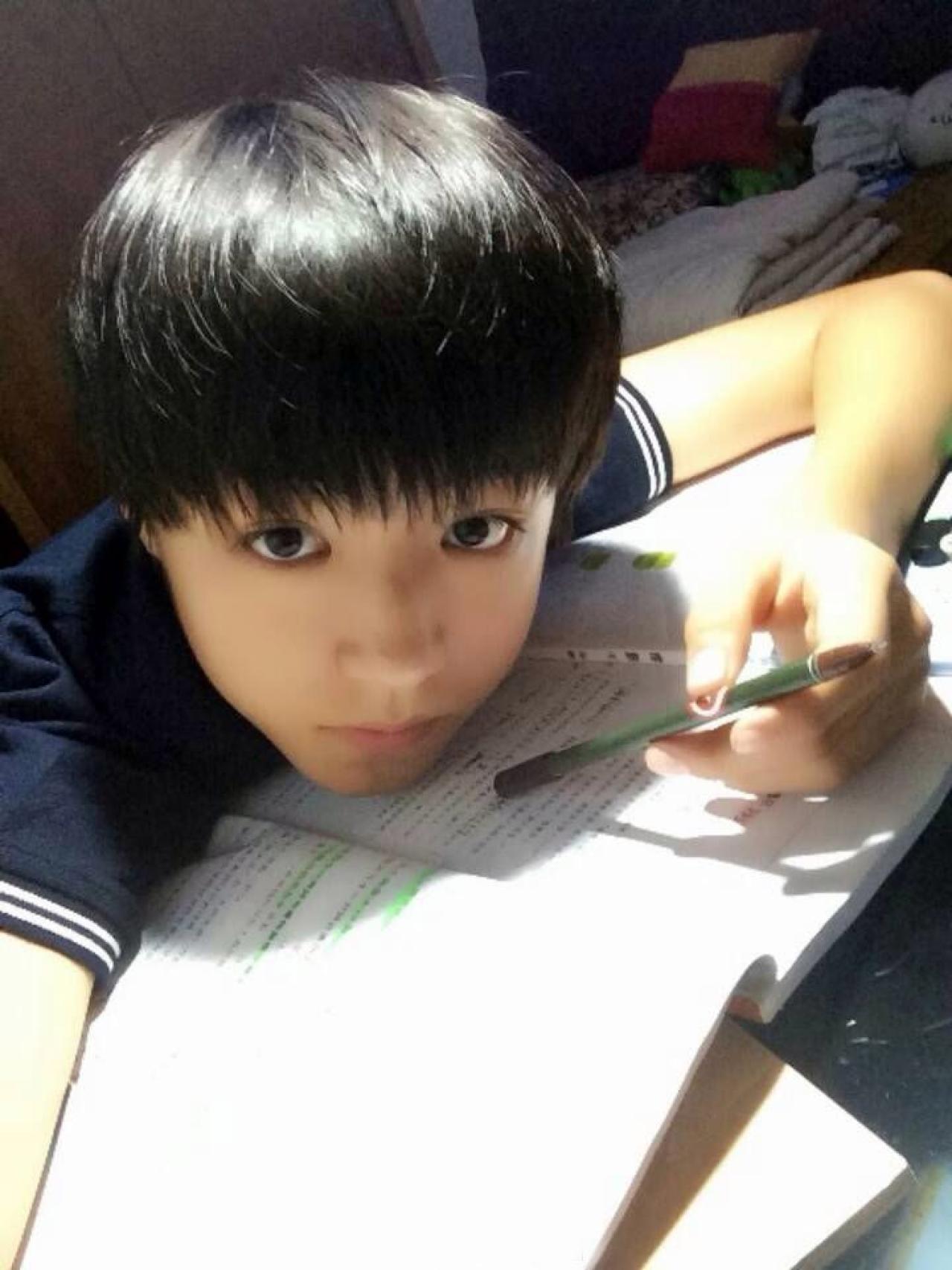 TFBOYS王俊凯扒在桌子上，转着笔