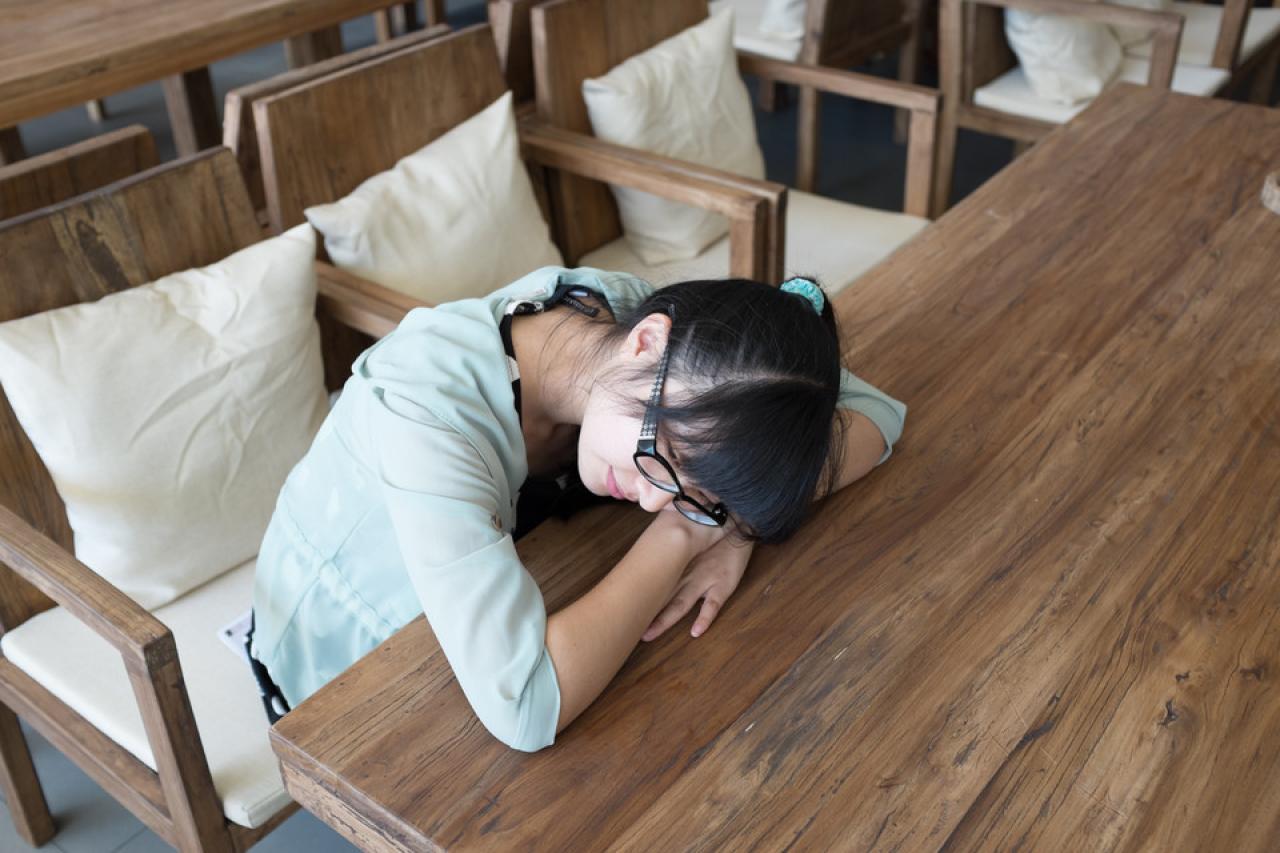 双手叠放在桌子傻瓜，头枕在手臂上