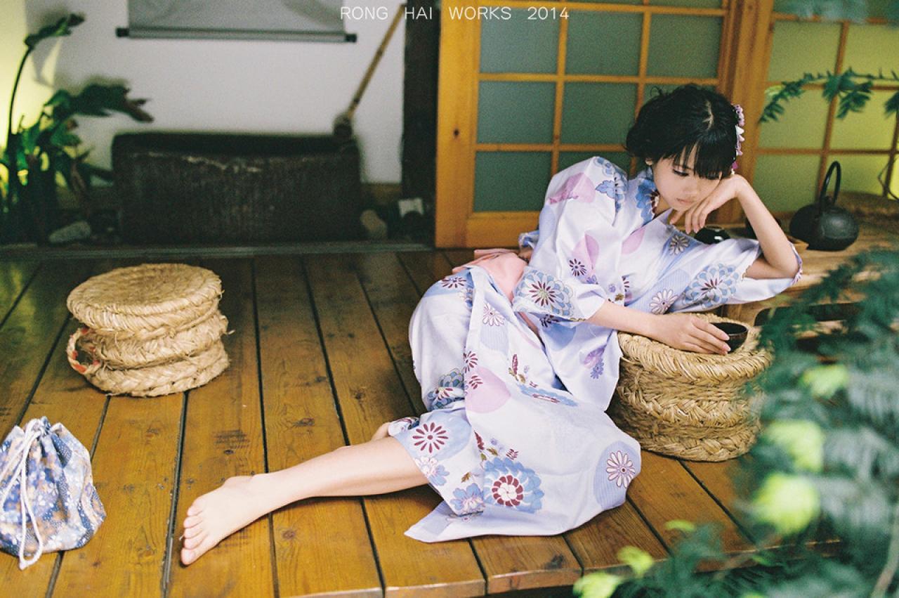 猫梓端着茶碗，手撑着头，斜躺在方桌上