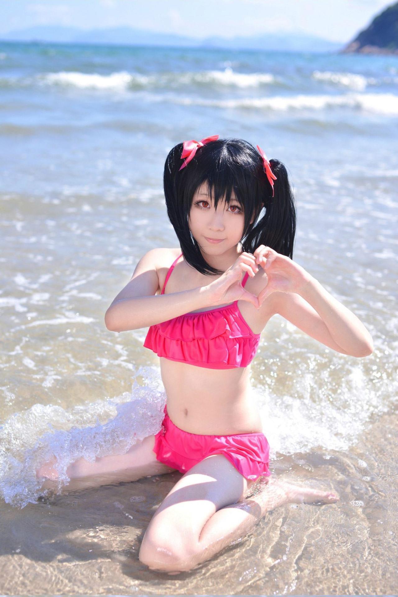 玛丽爷扮演矢泽妮可坐在海滩上作心形手势