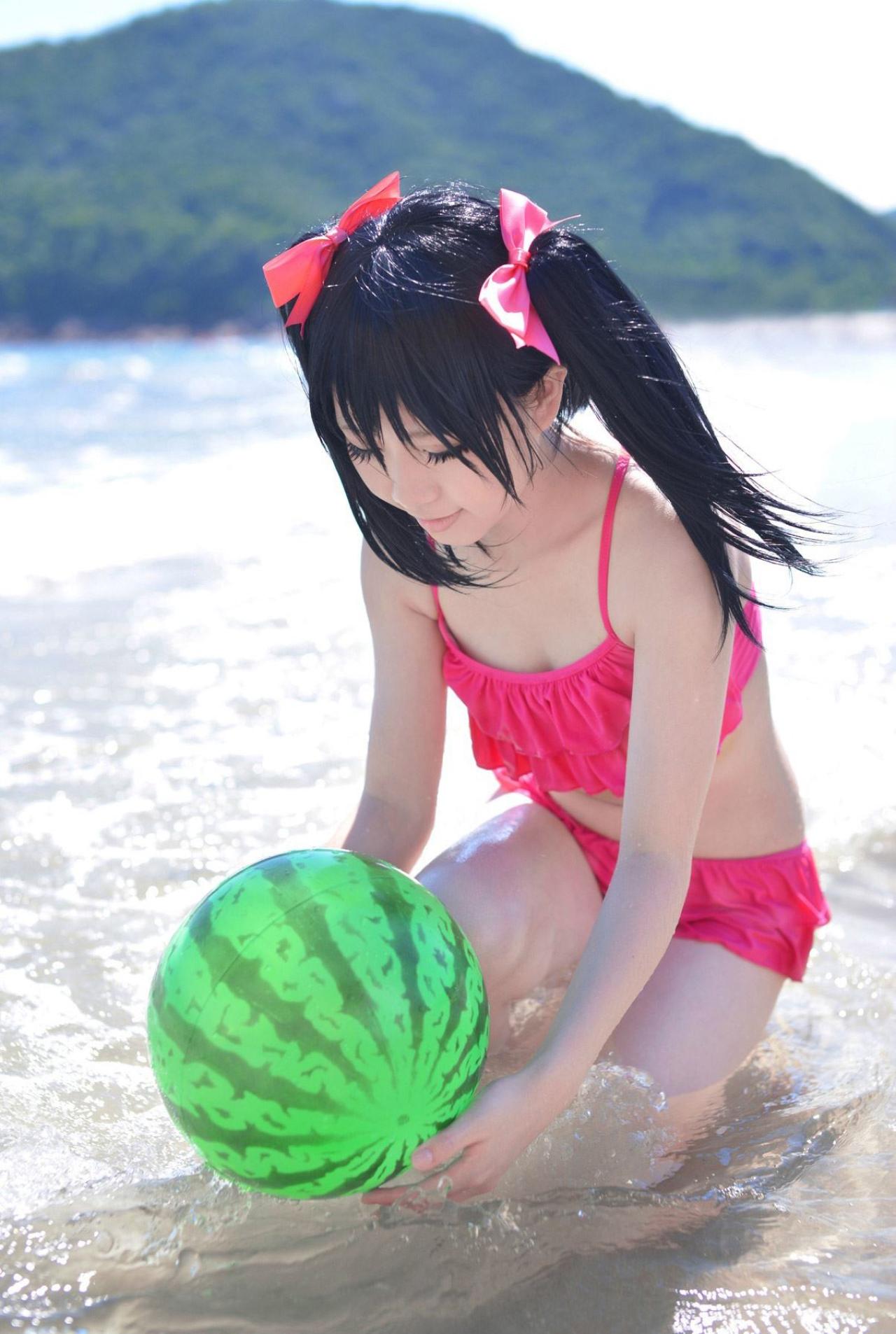 玛丽爷扮演矢泽妮可蹲在海边，海浪拍打着西瓜