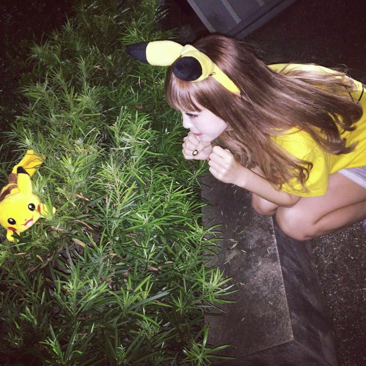 藤田ニコル扮成皮卡丘蹲在草丛旁，草丛里放着一只皮卡丘玩偶