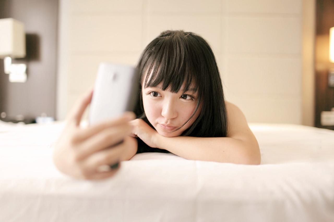 奈音蘑菇扒在床上，拿起手机嘟嘴自拍