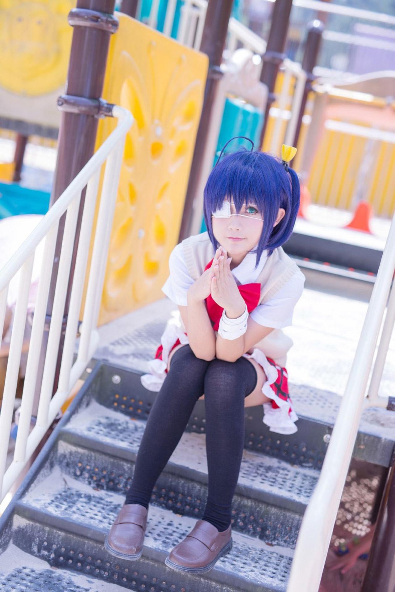 小野麻雀扮演小鸟游六花双手手指抵在一起坐在台阶上